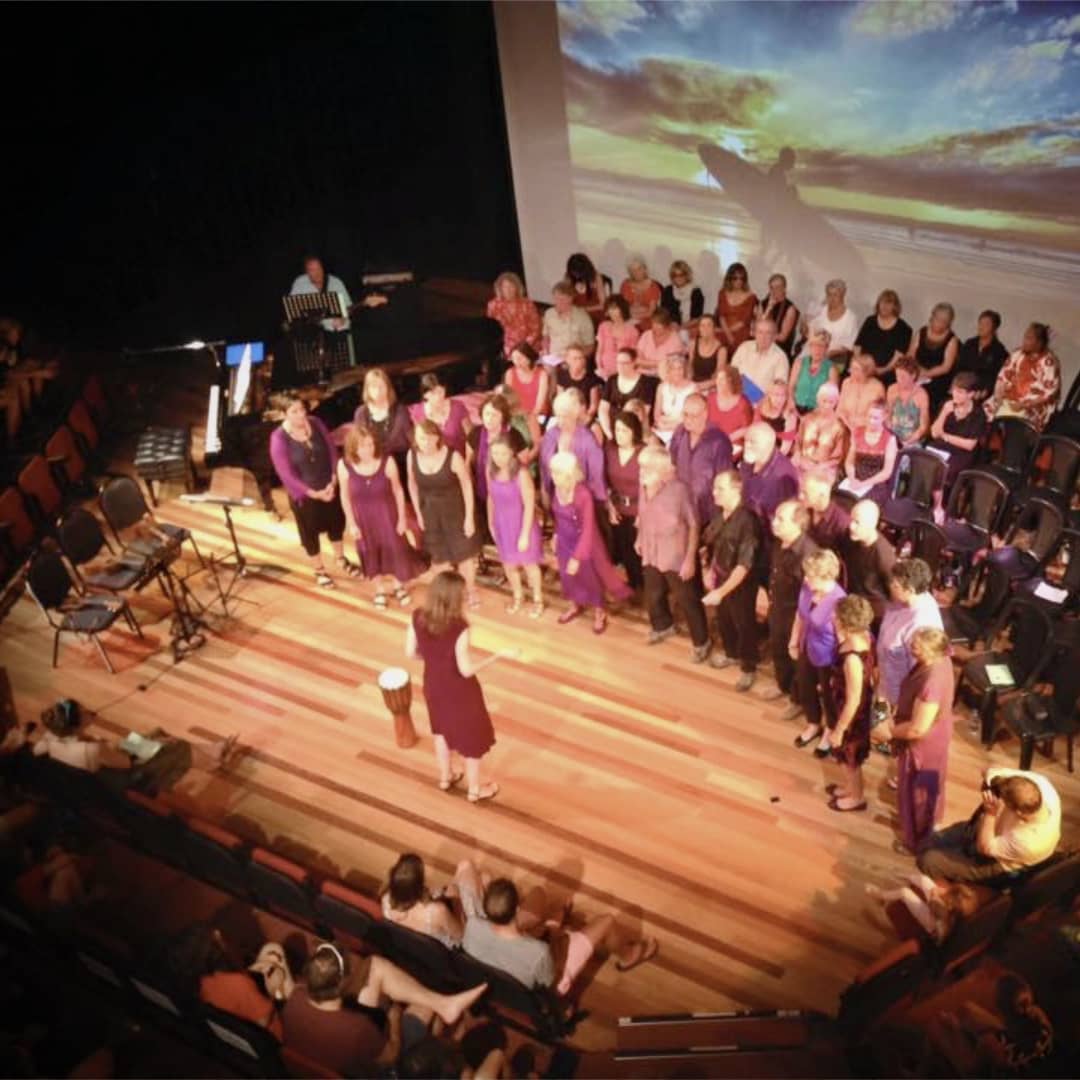 Aerial stage view of WolfSong choir singing at Byron Bay Theatre with audience visible