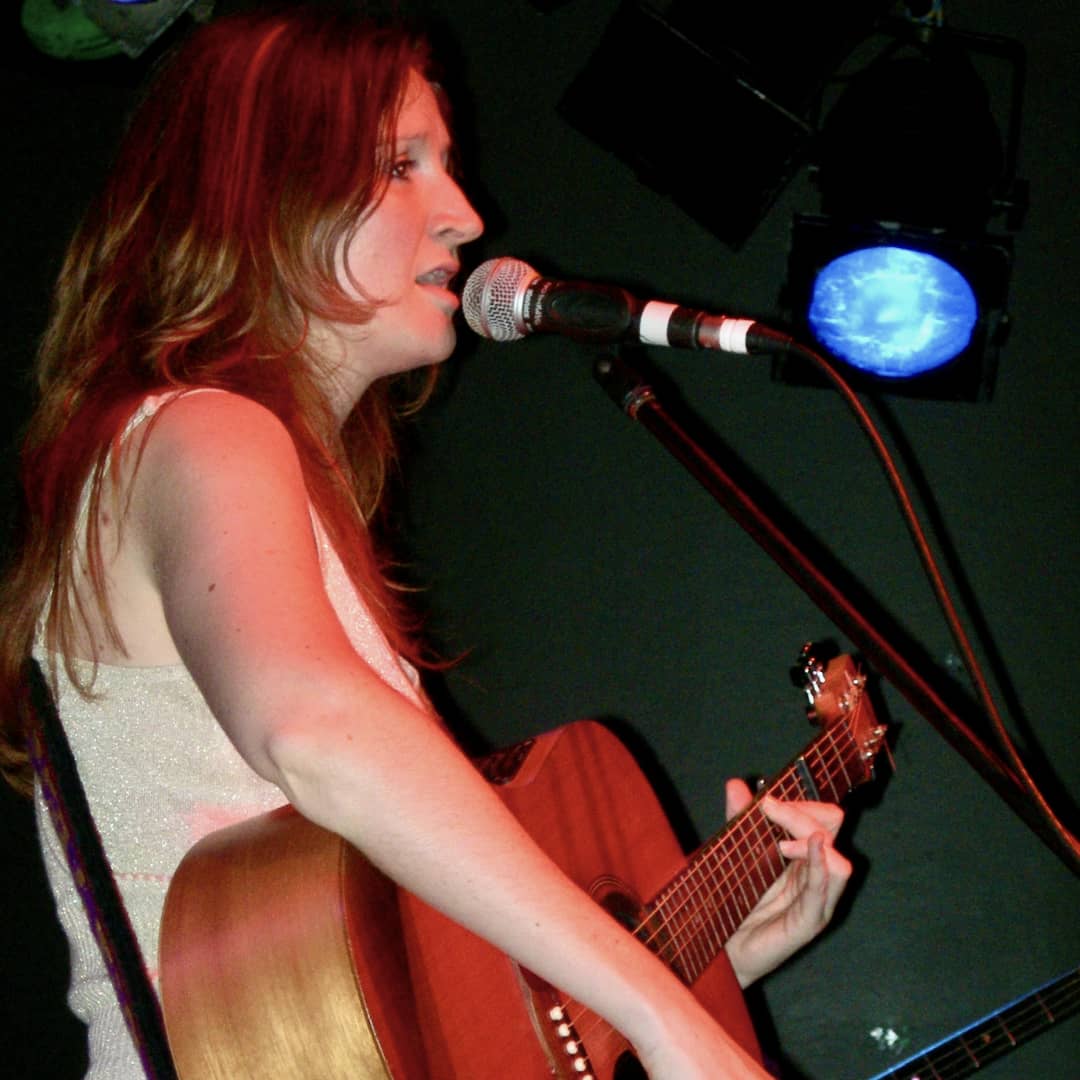 Imogen Wolf performing as a singer-songwriter on acoustic guitar