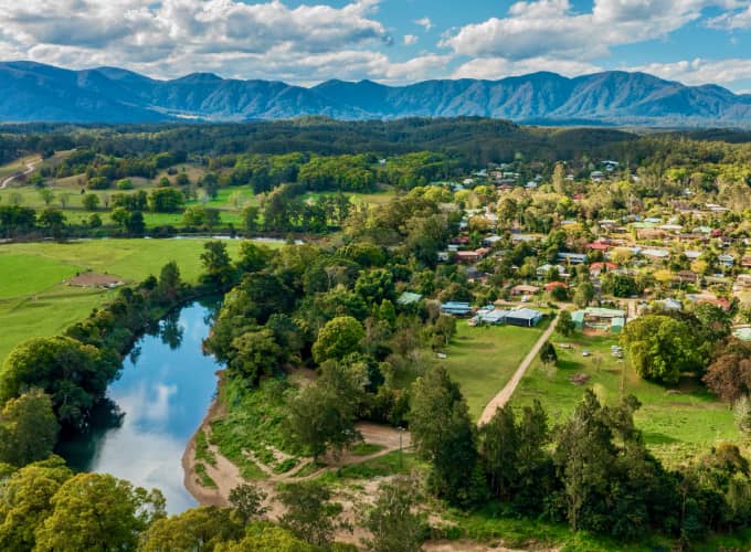 Aerial view of Bellingen NSW showing the river, farmland, and township with distant mountain range