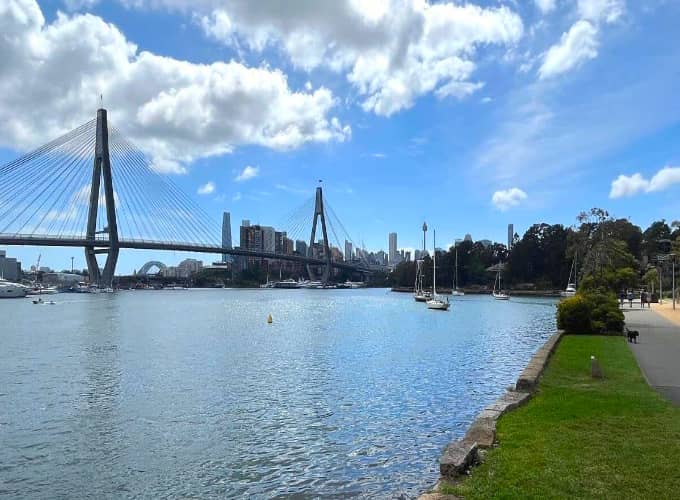 View across Rozelle Bay towards Anzac Bridge and the Sydney skyline on a bright sunny day.