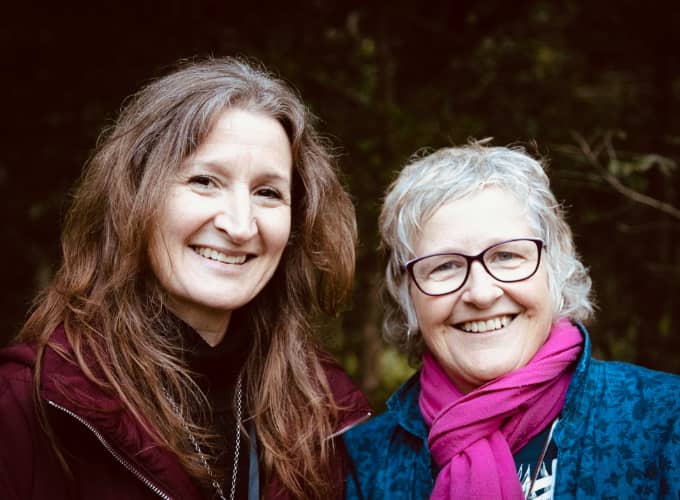 Two smiling women together, Imogen and Suze, leaders of the Feel Good Sing Thing.