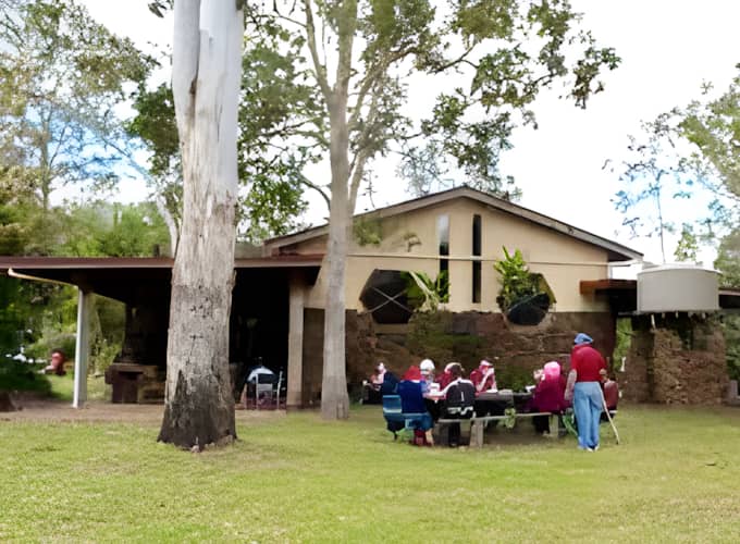 Participants seated at outdoor tables on the lawn outside Hanging Rock Hall during the retreat