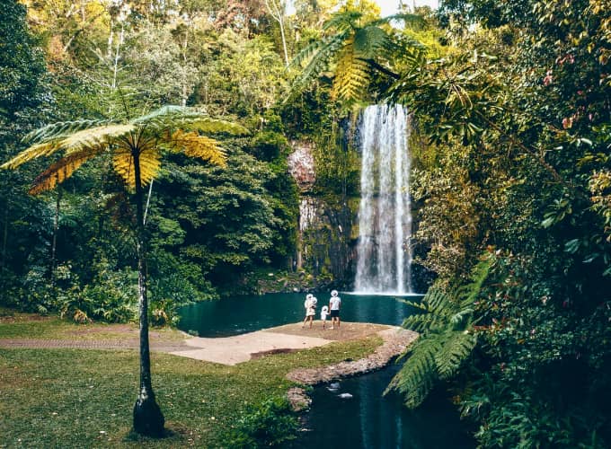 Rainforest waterfall and swimming hole in the Cairns hinterland with a small group standing on the rock ledge