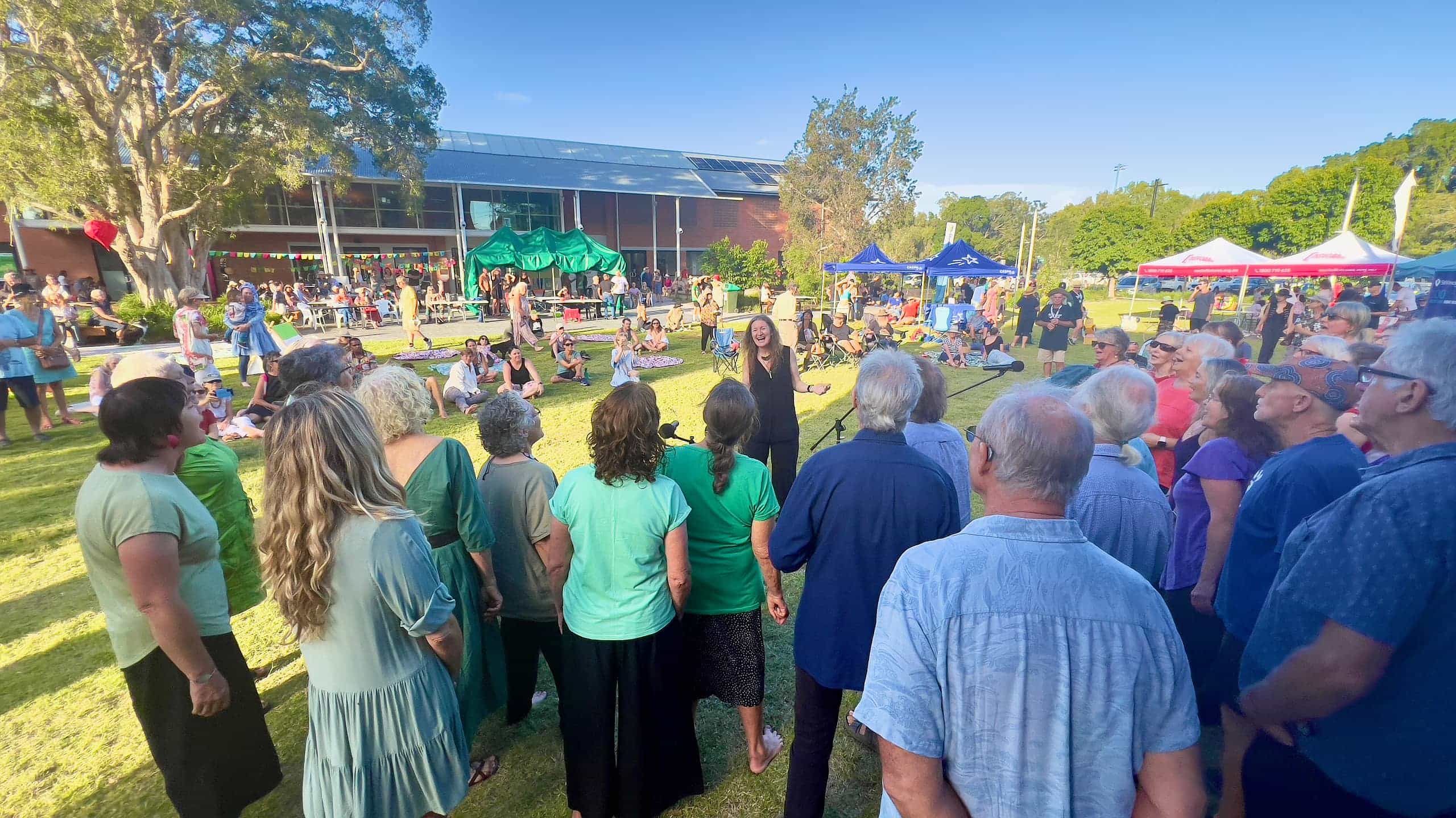 Imogen Wolf conducting a WolfSong performance in the Lismore Quad precinct with audience in background